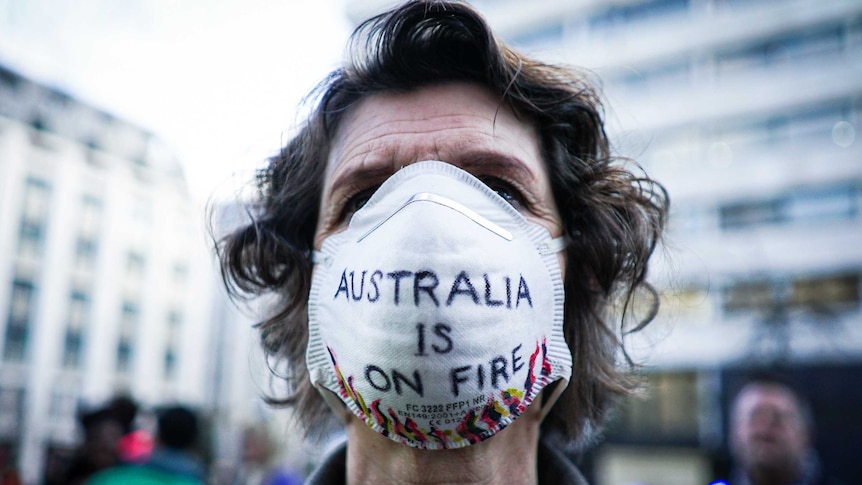 A woman wears a face mask with the words Australia is on fire on it