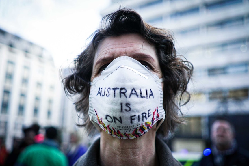 A woman wears a face mask with the words Australia is on fire on it