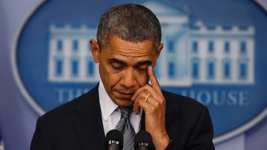 US President Barack Obama wipes at his eye during a press conference.