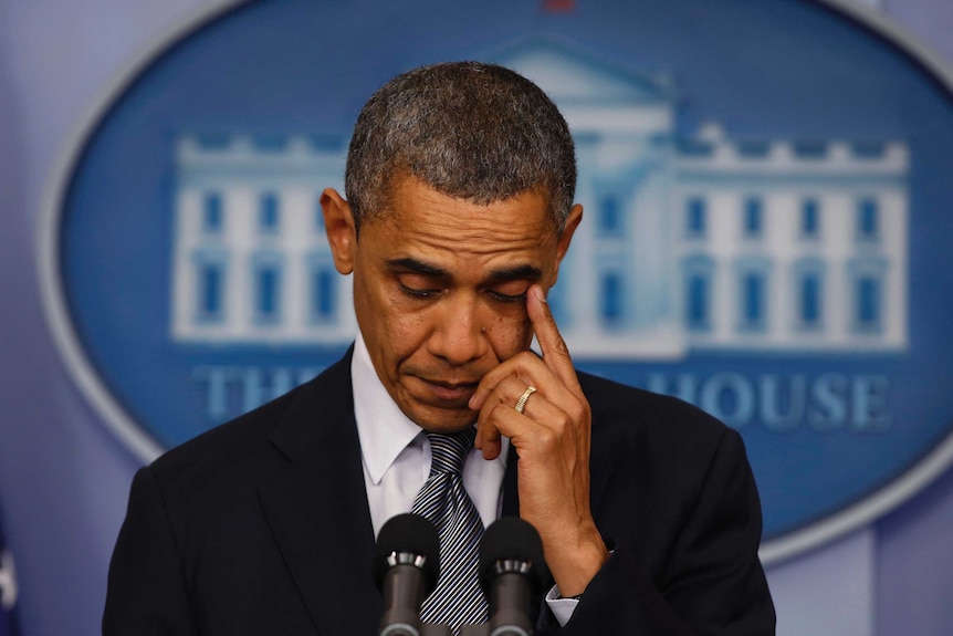 US President Barack Obama wipes at his eye during a press conference.