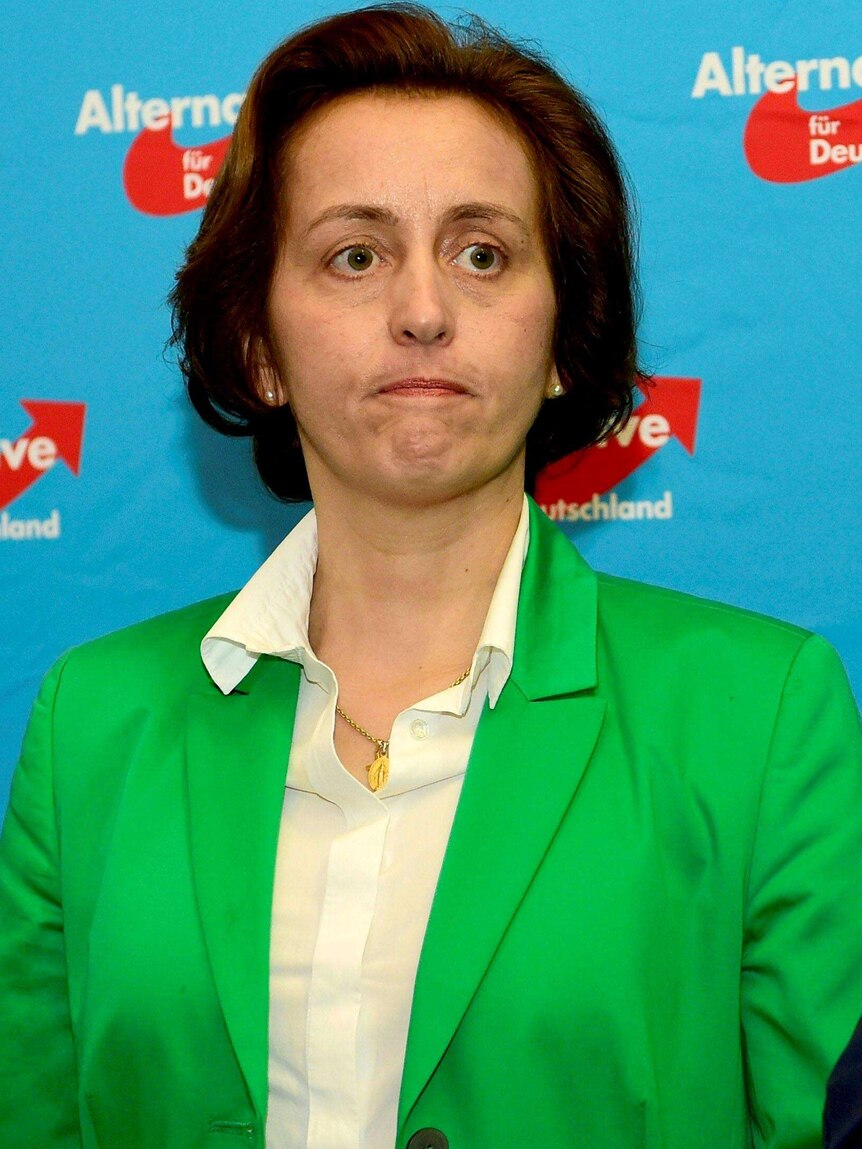 Upper body photo of Beatrix von Storch, wearing a bright green jacket and looking stern.