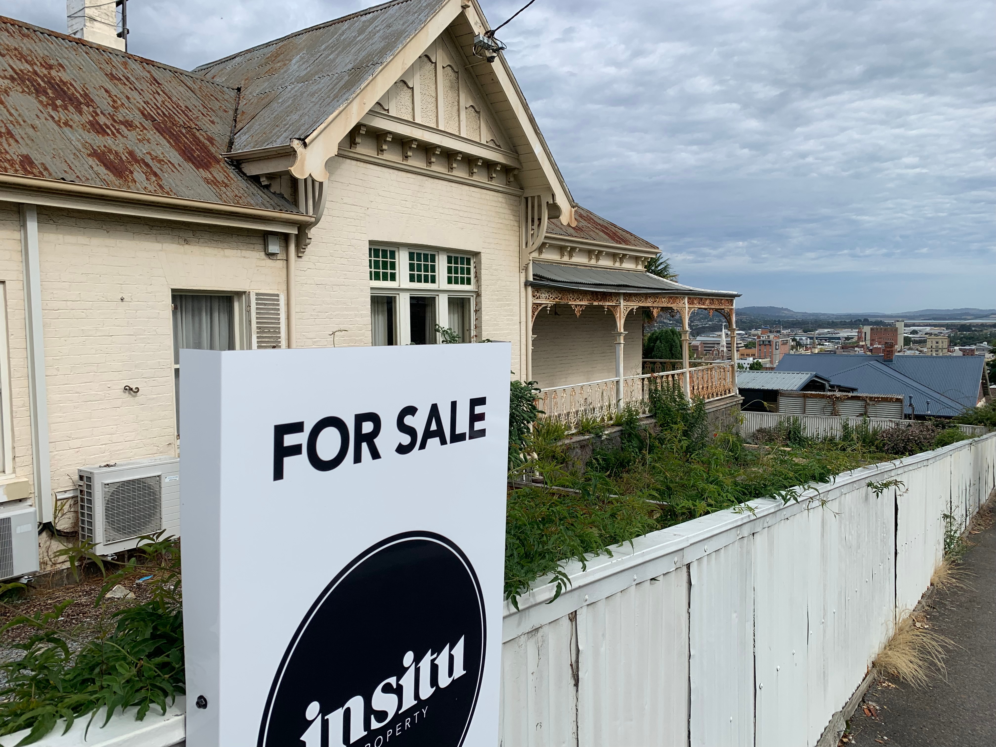 A for sale sign in front of a rundown house