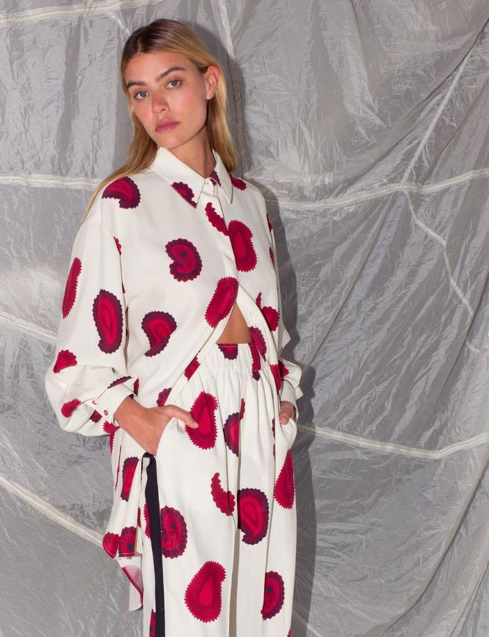 A woman wearing a white shirt with a large paisley pattern on it