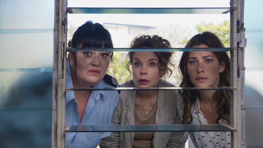 Katrina Milosevic, Sigrid Thornton and Brooke Satchwell look through a window towards the camera, looking concerned