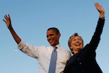 Barack Obama and Hillary Clinton embrace each other and wave.