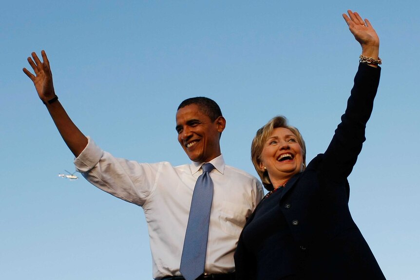 Barack Obama and Hillary Clinton embrace each other and wave.