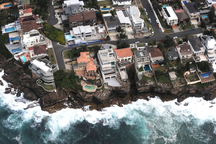 Una vista aérea de las casas en lo alto de un acantilado y del océano.