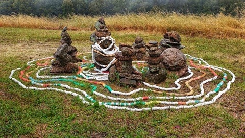 Wreaths of plastic bread tags adorn some rocks in a field
