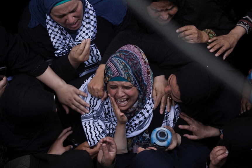 A group of women are seen weeping in mourning.