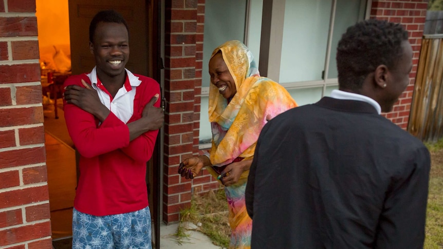 Akang shares a laugh with his mother and brother on the front stoop.