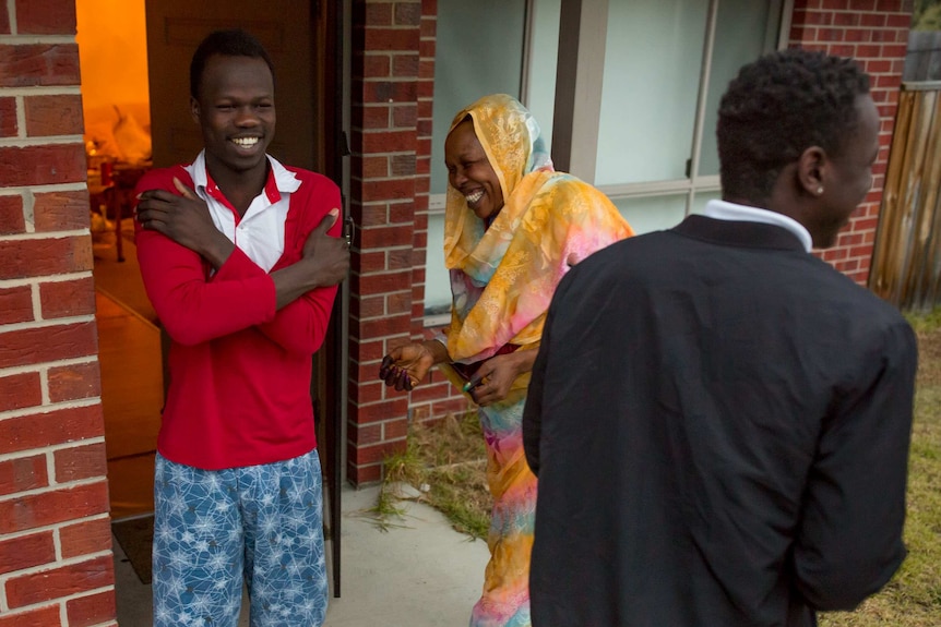Akang shares a laugh with his mother and brother on the front stoop.