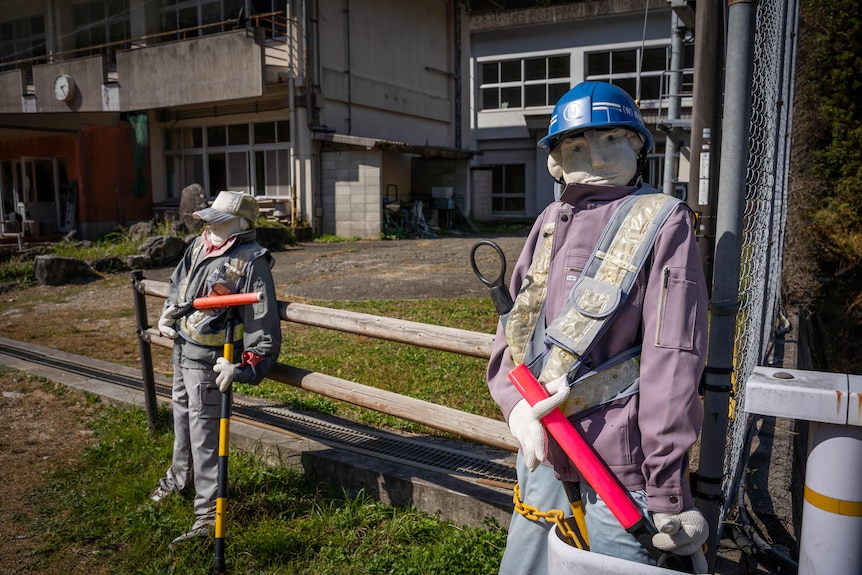 Dos trabajadores vestidos con uniformes de construcción, con cascos y rodillos de pintura.