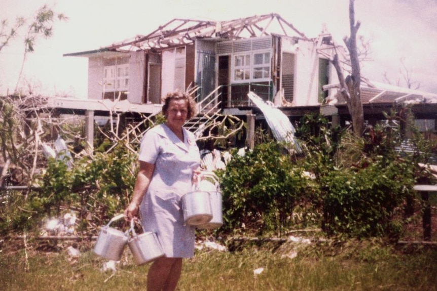 Red Cross volunteer in front of cyclone-torn house