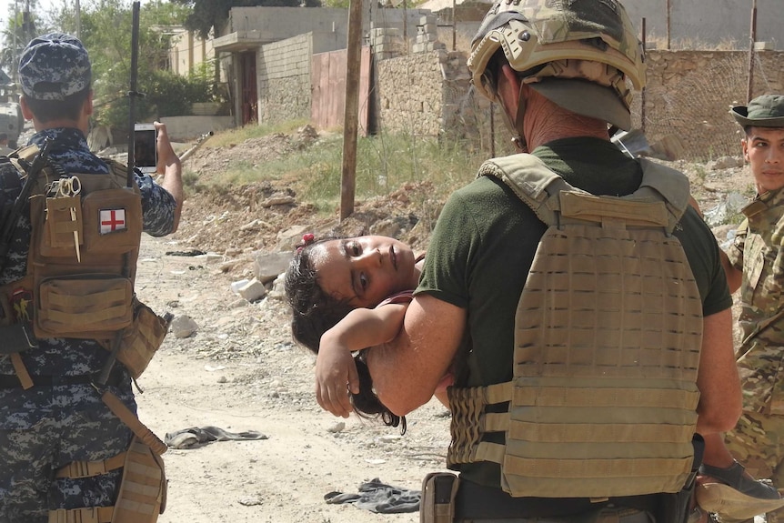David Eubank carrying an injured young Iraqi girl in Mosul