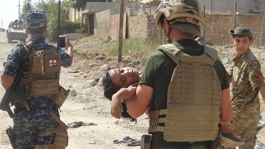 David Eubank carrying an injured young Iraqi girl in Mosul