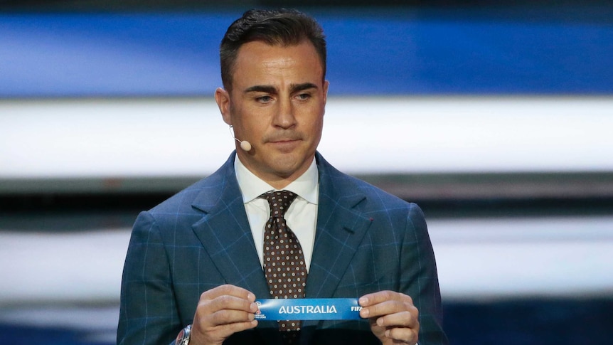 Former Italian soccer international Fabio Cannavaro holds up the team name of Australia.