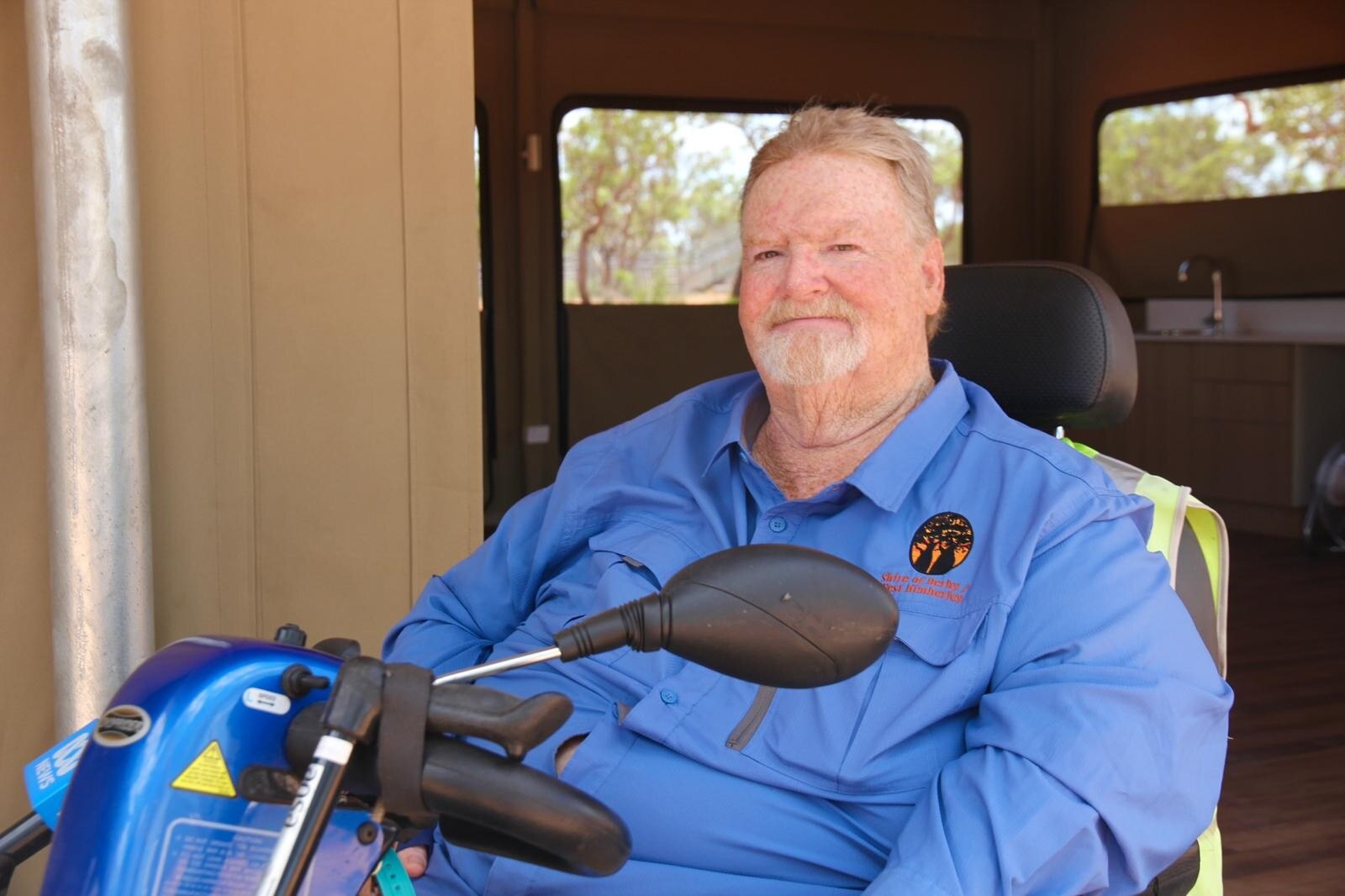 Un hombre sonriente de mediana edad se sienta en un scooter eléctrico.