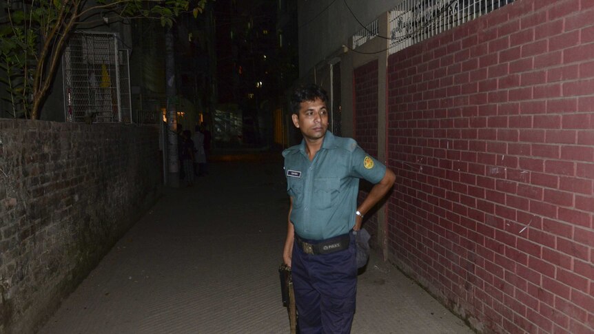 A police officer stands in front of an apartment building.