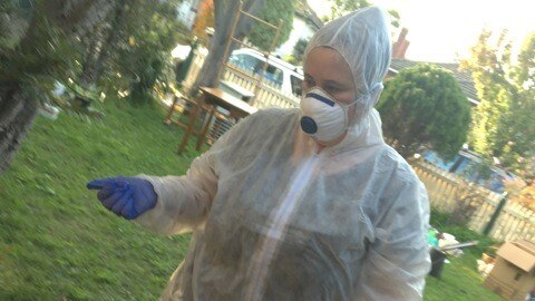 A woman wearing a protective suit to shield her from asbestos in her home.