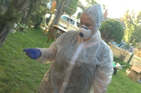 A woman wearing a protective suit to shield her from asbestos in her home.