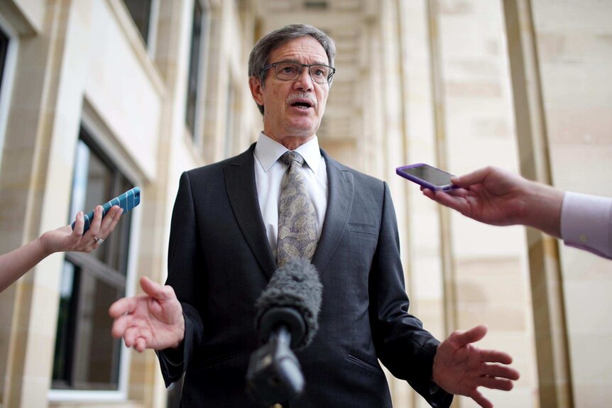 Low shot of WA Treasurer Mike Nahan, with reporters' phones outstretched, outside State Parliament in Perth