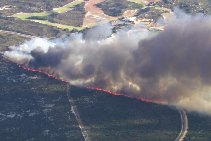 An aerial photo of flames burning in a line towards the coast