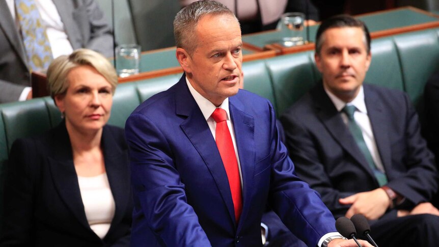 Opposition Leader Bill Shorten delivers his budget reply speech wearing a navy suit and red tie