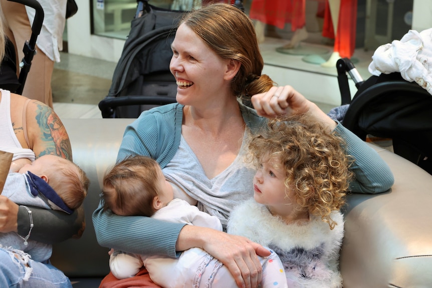 A woman breastfeeding her baby and smiling