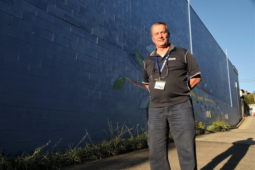 Man smiles to camera with his shadow behind him