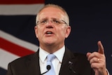Prime Minister Scott Morrison gestures during a speech claiming victory in the federal election in front of the Australian flag.
