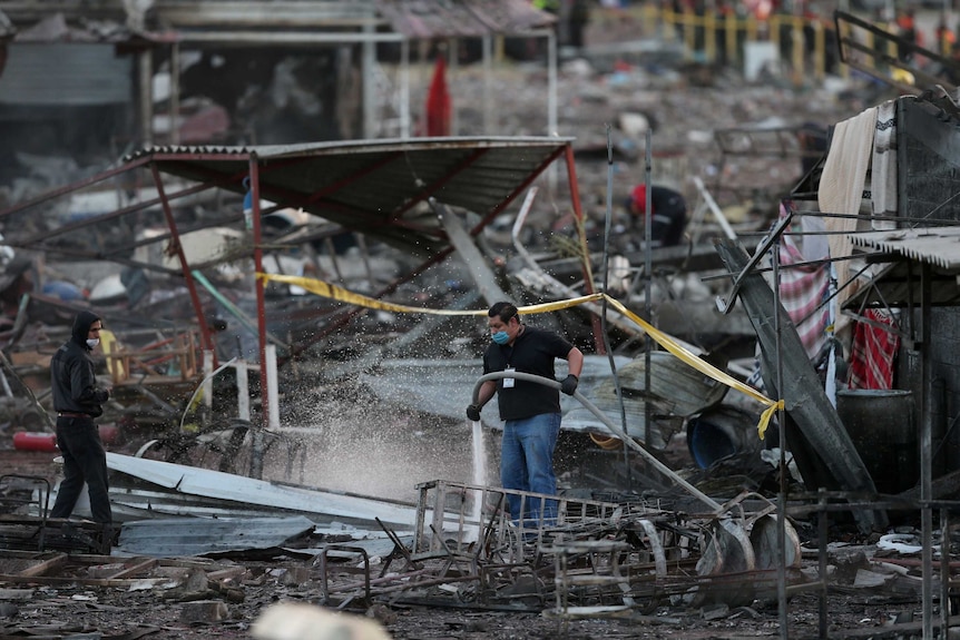 A man uses a water house after the explosion at the San Pabilto fireworks market on the outskirts of Mexico City.