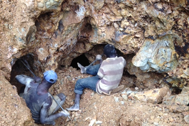 Two men chip away at the mountain near the road that leads to Panguna mine