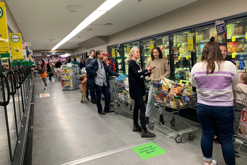 A line of shoppers with their trolleys.