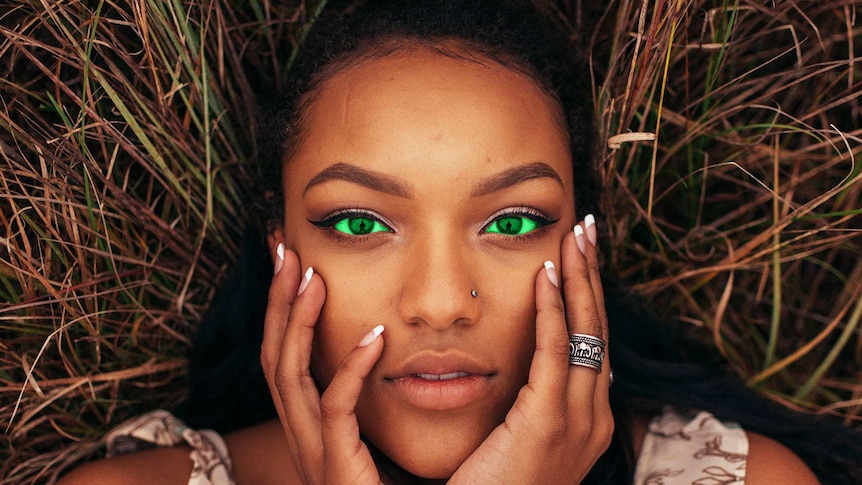 Woman with bright green eyes holding her face in a story about dealing with jealousy in a relationship.