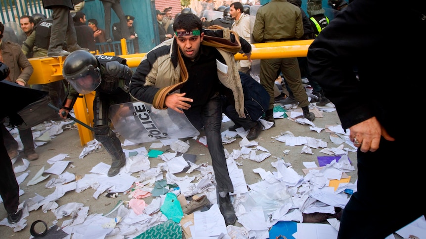 Police chase protesters as they enter the gate of the British embassy in Tehran