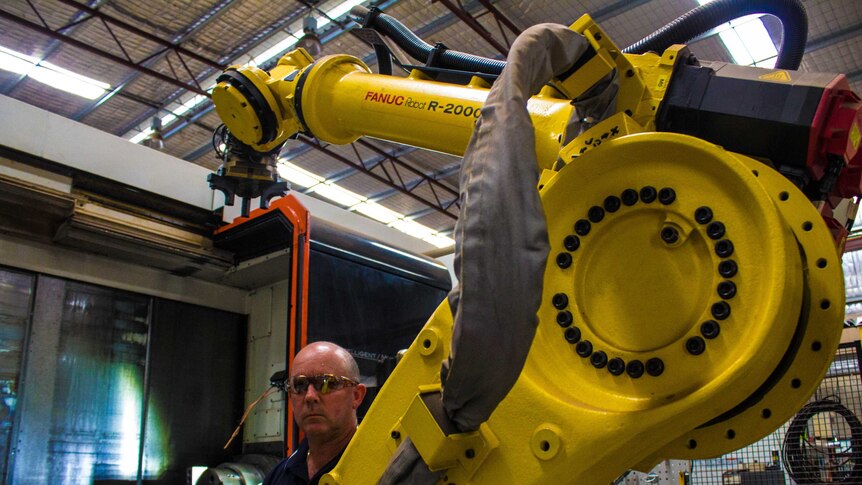 Harlsan Industries managing director Harley Hollier stands next to a robotic machining centre at his West Kalgoorlie workshop.
