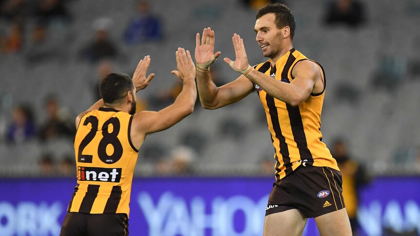 Two AFL teammates high five each other after a goal.
