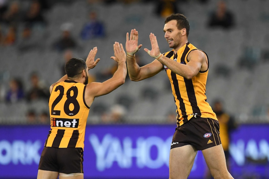 Two AFL teammates high five each other after a goal.