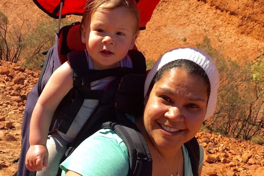 Toddler in backpack carried by woman in white beanie