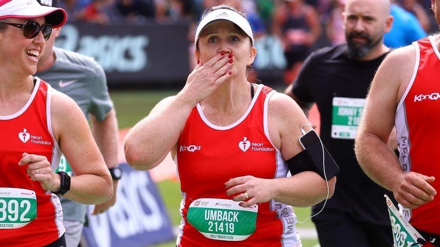 a woman dressed in running gear appearing to blow a kiss to the crowd a woman dressed in matching outfit to her left