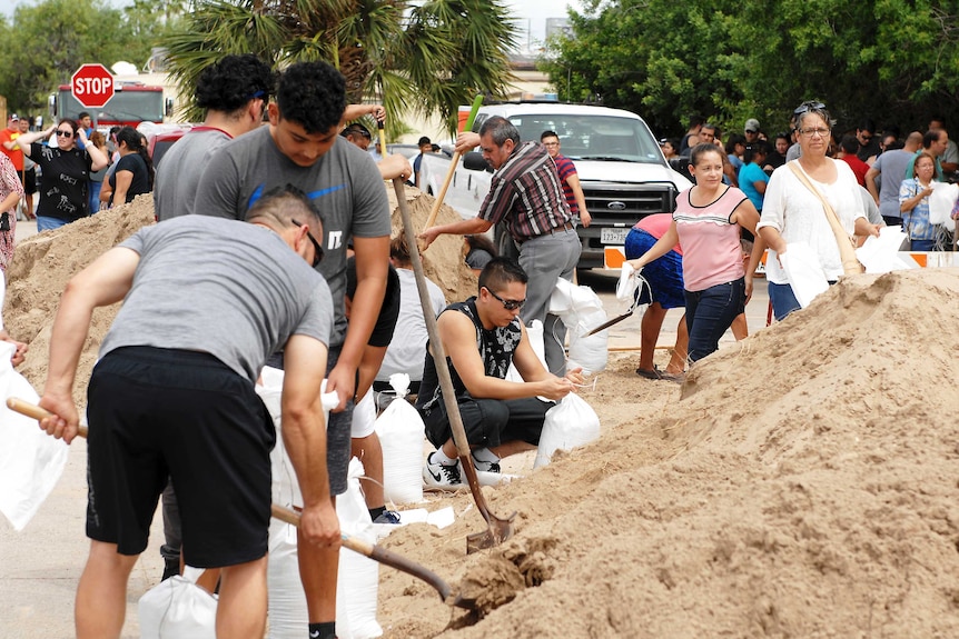 Residents fill sandbags while others wait in line.