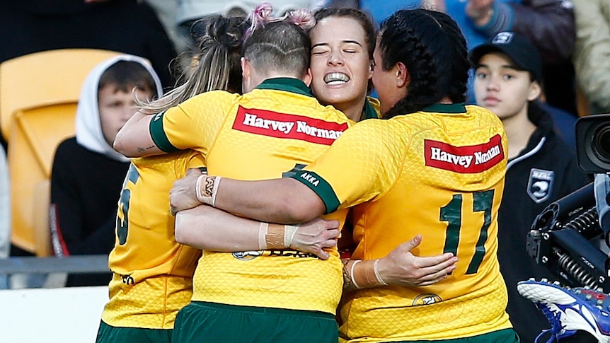 Isabelle Kelly celebrates a try for Australia with teammates against New Zealand.