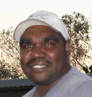 retrato de um homem aborígine com sobrancelhas espessas e boné branco