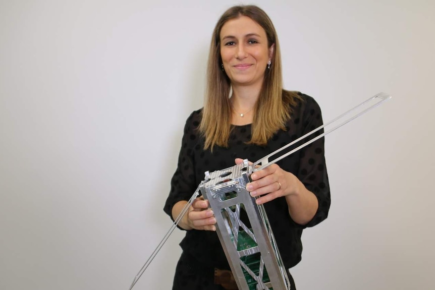 Flavia Tata Nardini holds a model of a satellite.
