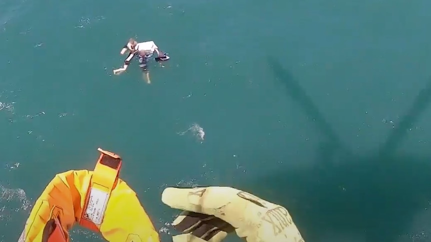 Aerial view of four people around a square item in ocean