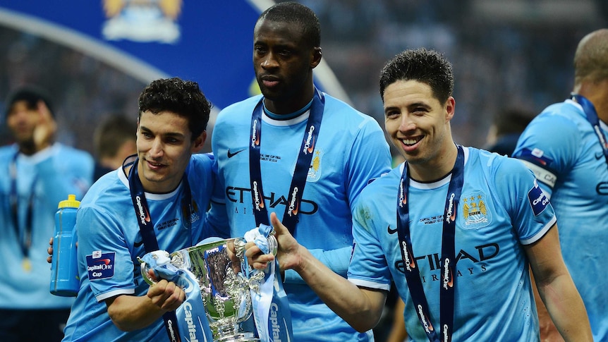 jesus Navas, Yaya Toure and Samir Nasri of Manchester City pose with the League Cup trophy.
