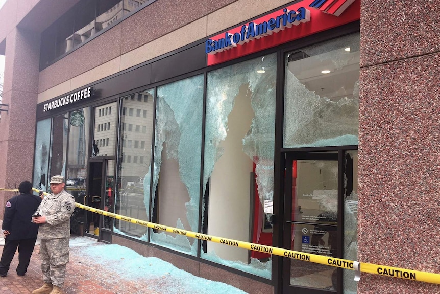 Security guards the front of a Bank of America and Starbucks outlet which have smashed windows.