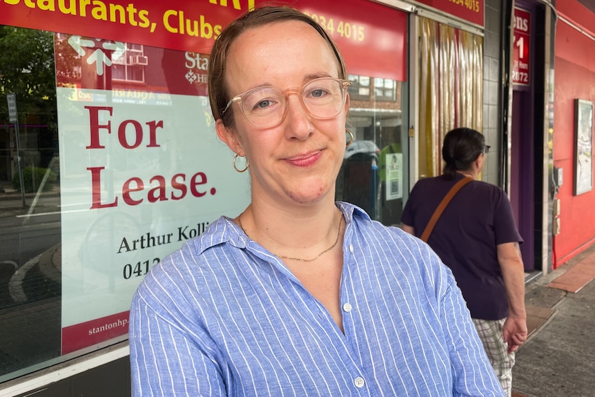 A woman wearing glasses stood in front of a shop window