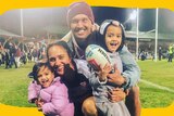 Tazmin Gray with Anthony and two kids standing on a rugby field with bright lights at night. A crowd is behind them.