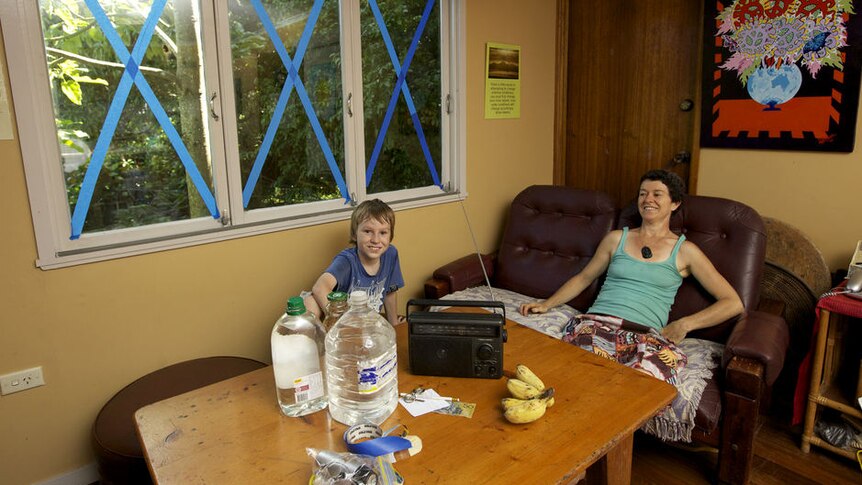 Mother and son sit in lounge room after taping windows before Cyclone Yasi arrives.